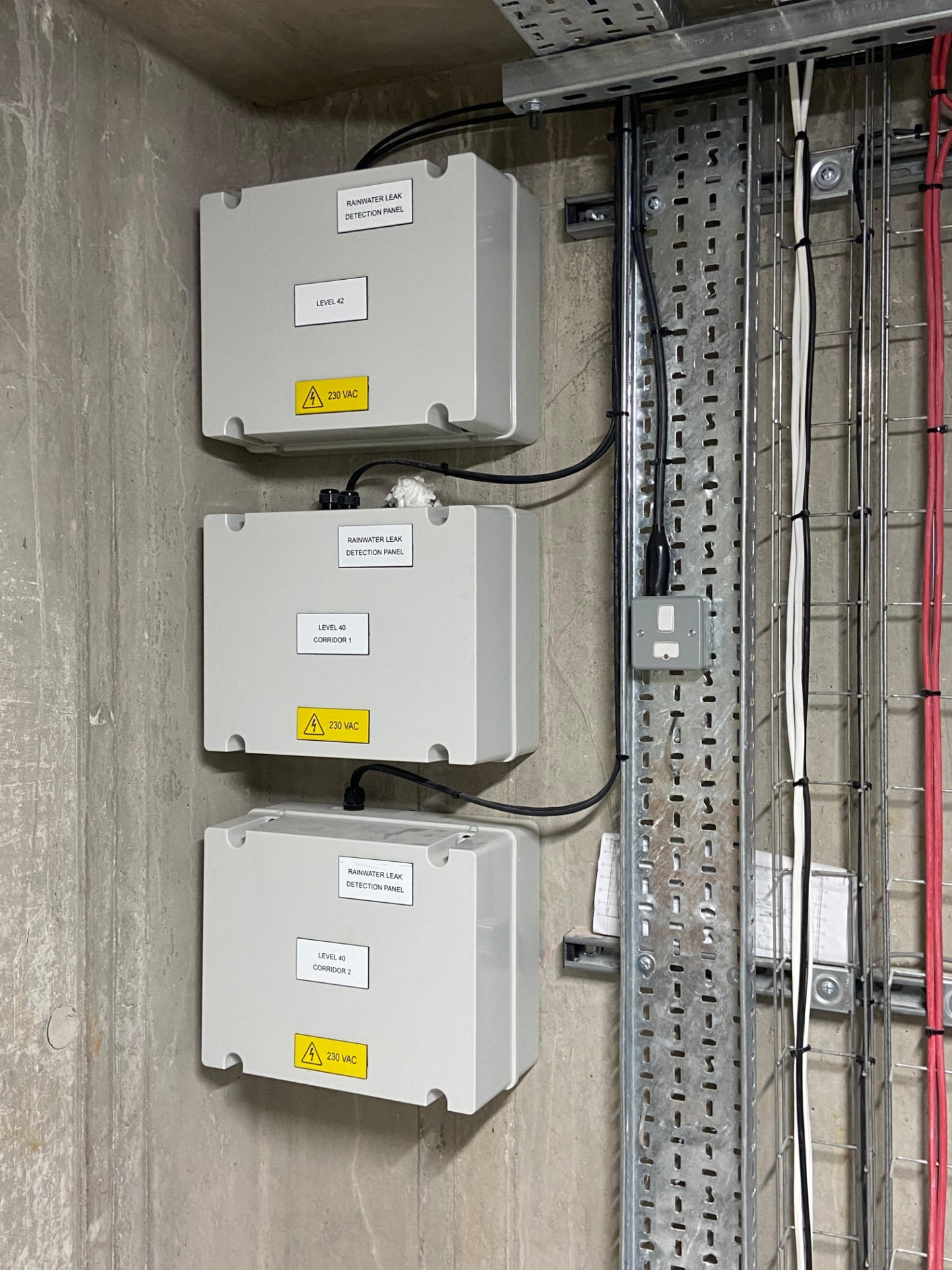 Wall-mounted rainwater leak detection panels installed alongside containment and cabling